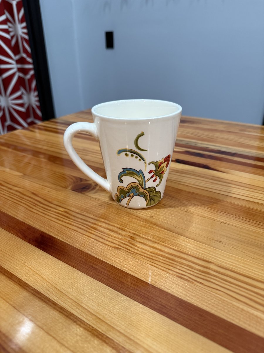Original phone photo of a white ceramic mug on a wooden table